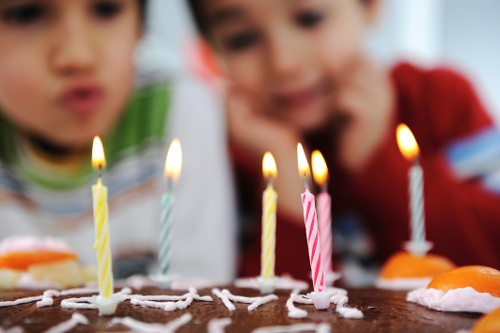 Two little boys blowing candles on cake, happy birthday party kids