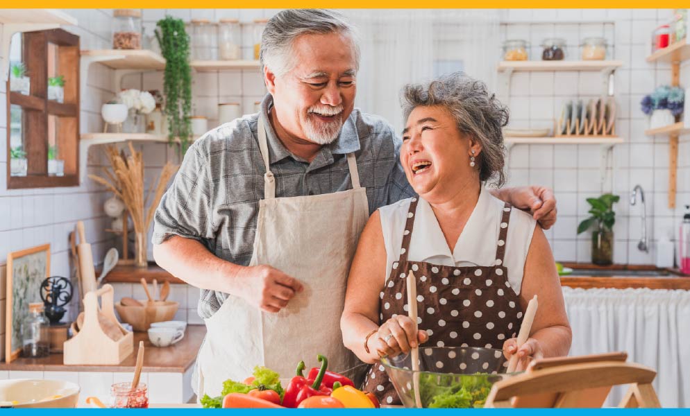Laughing elder asian man and woman couple in the kitchen cooking together Laughing elder asian man and woman couple in the kitchen cooking together